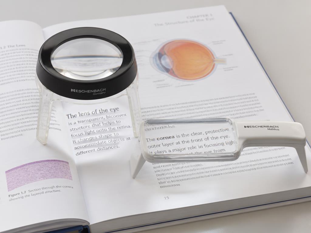 Dome stand magnifier and bar magnifier resting directly on an open book page at a fixed focal distance